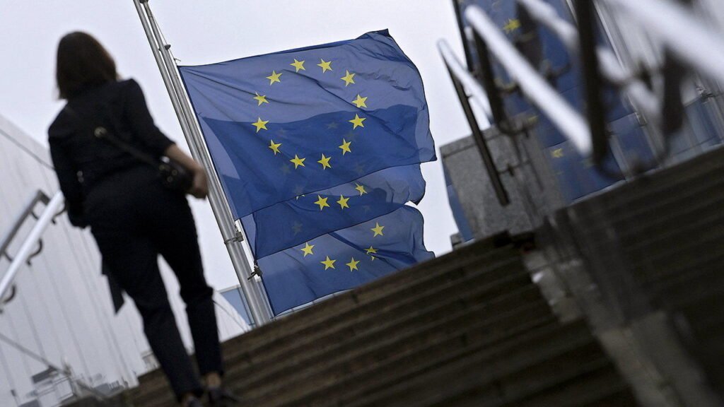 A woman climbs stairs next to European flags.