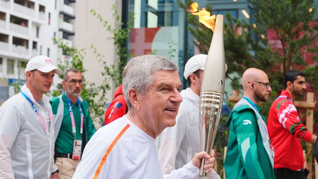 IOC president Thomas Bach carries the Olympic torch