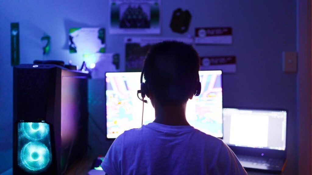 Young child is seen using a computer in a darkened room