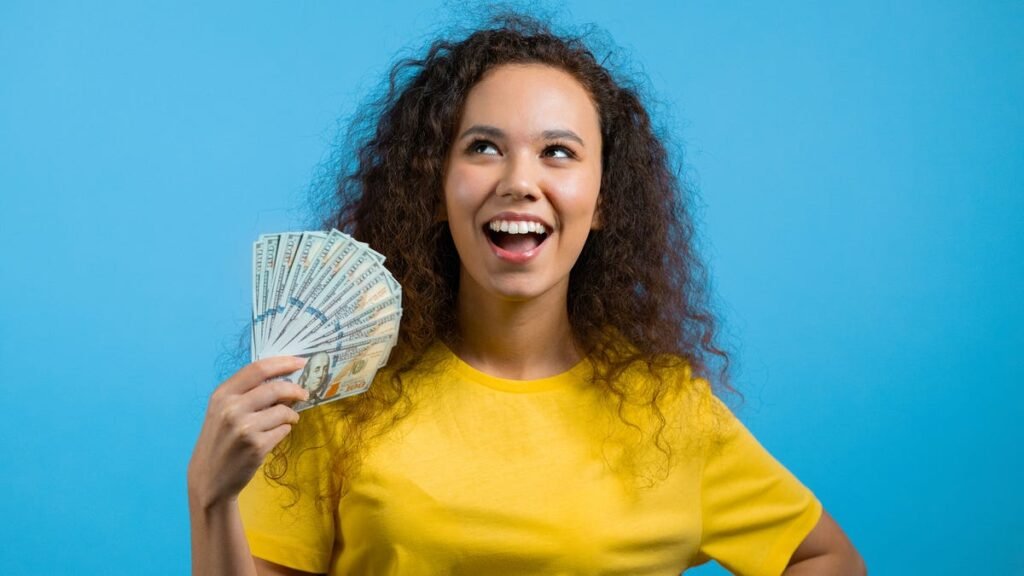 girl in yellow shirt on blue background fanning money