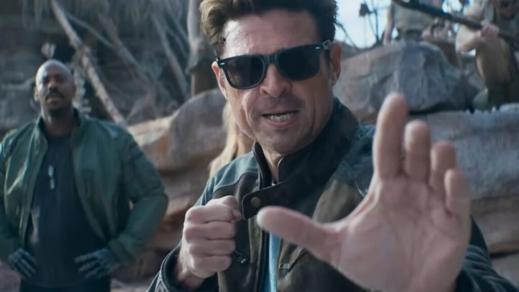 dark haired man in glasses and leather jacket raising his hands for a fight.